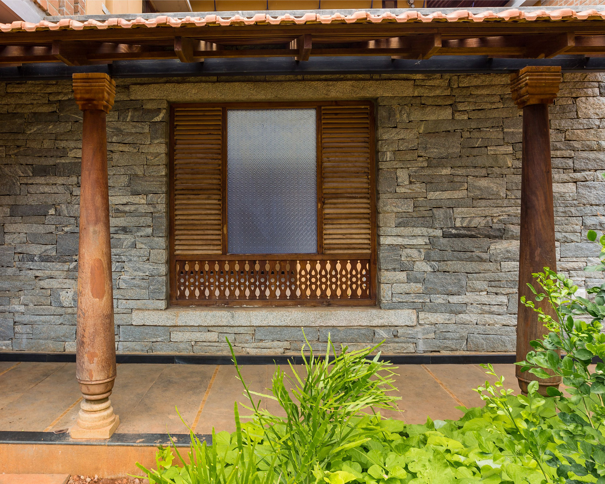 Wooden pillars and jaali at the entrance of a house at Good Earth Malhar